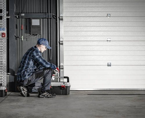 Caucasian Technician in His 40s Servicing Commercial Dock Garage Gate. Industrial Theme.