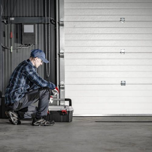 Smith Door Caucasian Technician in His 40s Servicing Commercial Dock Garage Gate. Industrial Theme.