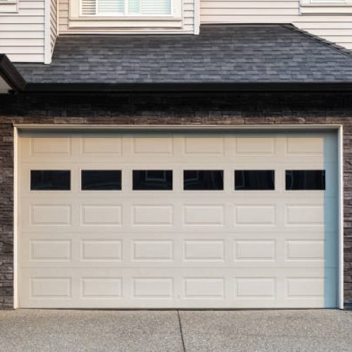 now Garage Door. Modern house with garage door that is closed. A perfect neighborhood. Family house with wide garage door and concrete driveway in front. Street photo, nobody