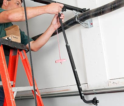 A worker is replacing the traveler car on a belt driven garage door opener.